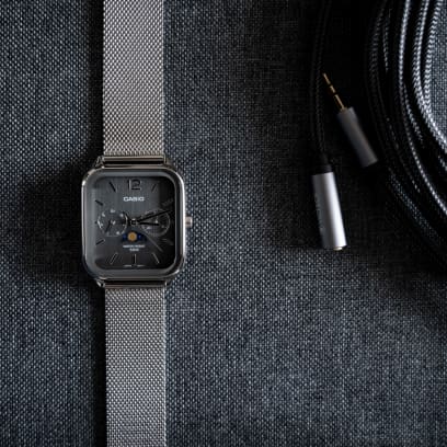 Ansicht der flach liegenden CASIO TIMELESS COLLECTION Armbanduhr MTP-M305M-8AV auf grauem Textiluntergrund neben einem in grauem Textil ummantelten Verlängerungskabel.