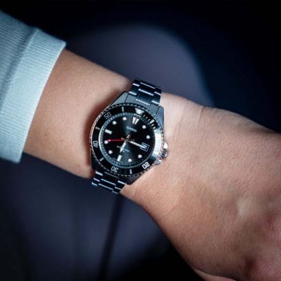 Nahaufnahme der MDV-10D-1A1V Armbanduhr mit silberfarbenem Armband und schwarzem Gehäuse am Handgelenk einer Frau.