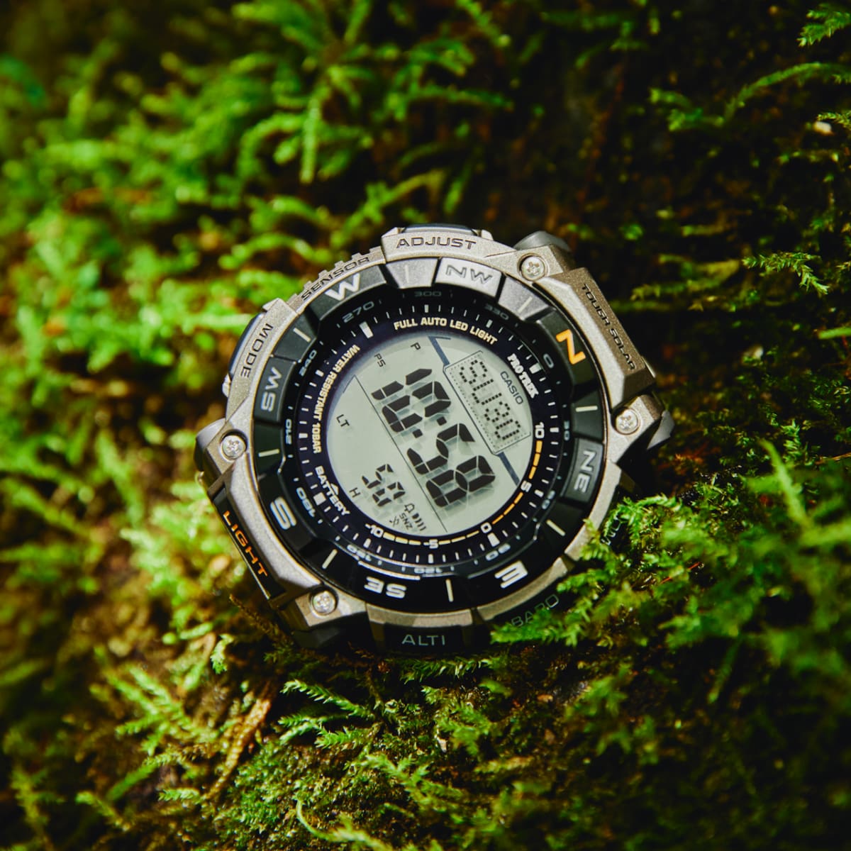 Die PRO TREK Armbanduhr PRG-340T-7 seitlich liegend auf einem moosigen Boden drapiert.