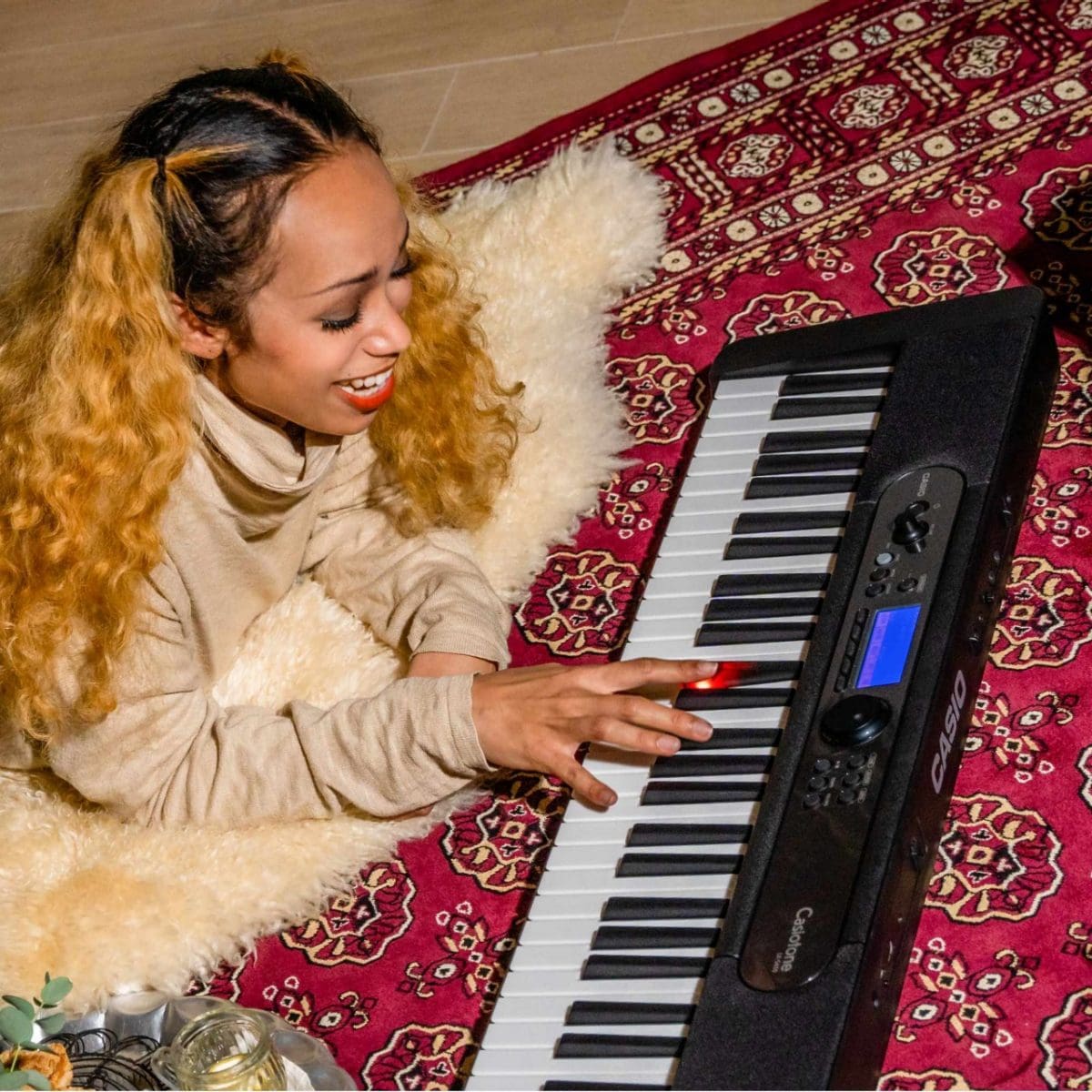 Mujer tocando el teclado CASIO LK-S450 con teclas luminosas.