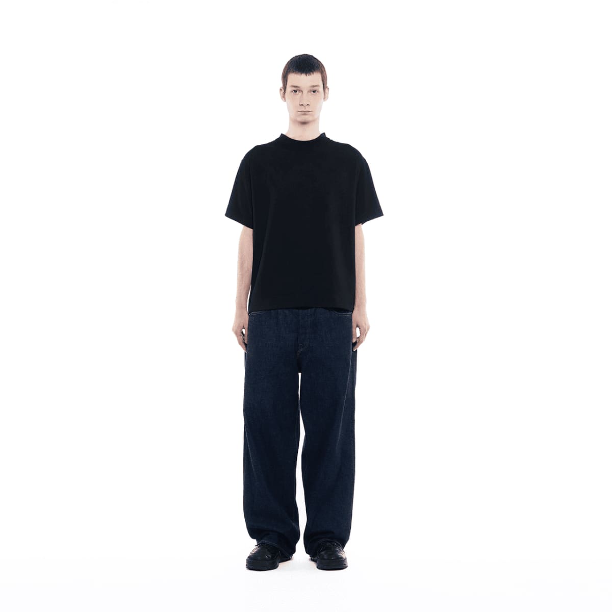 Un hombre que lleva vaqueros oscuros viste una camiseta de GXFAB.