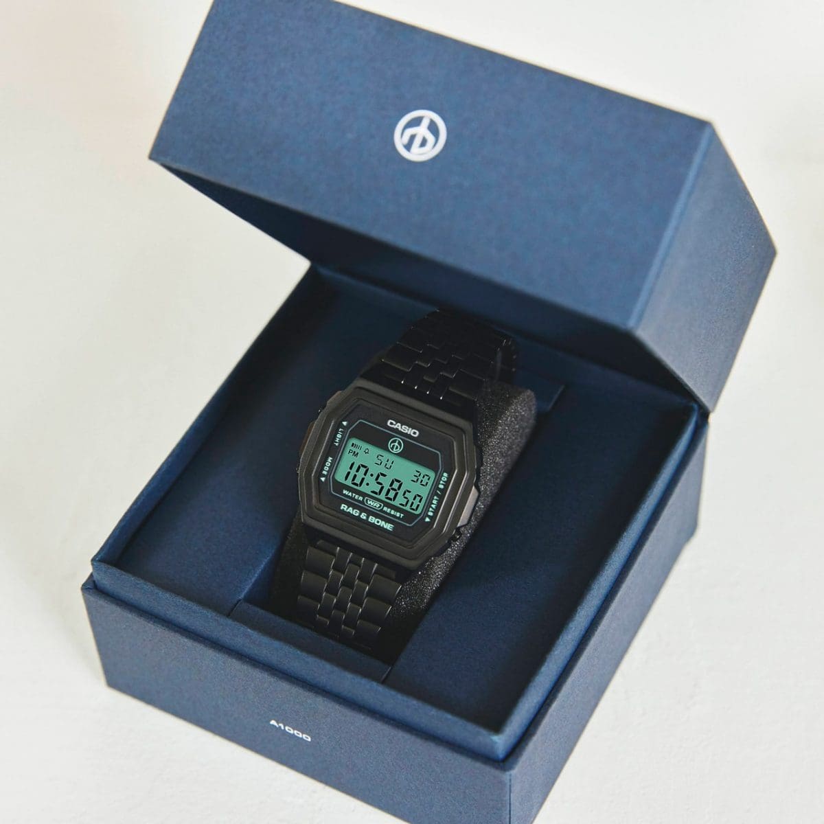 El reloj digital A1000RCB negro en su caja de embalaje azul