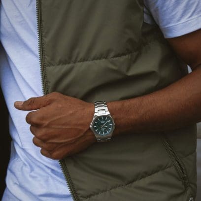 El EFR-S108DE-3AVUEF en la muñeca de un hombre que viste un chaleco acolchado verde oliva