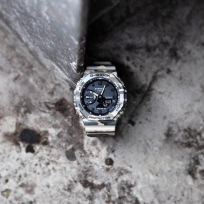 El reloj de pulsera G-SHOCK GA-2100CM-5AER está apoyado sobre una superficie de piedra.