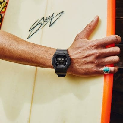 El GBX-100NS-1ER en la muñeca de un hombre que sostiene una tabla de surf