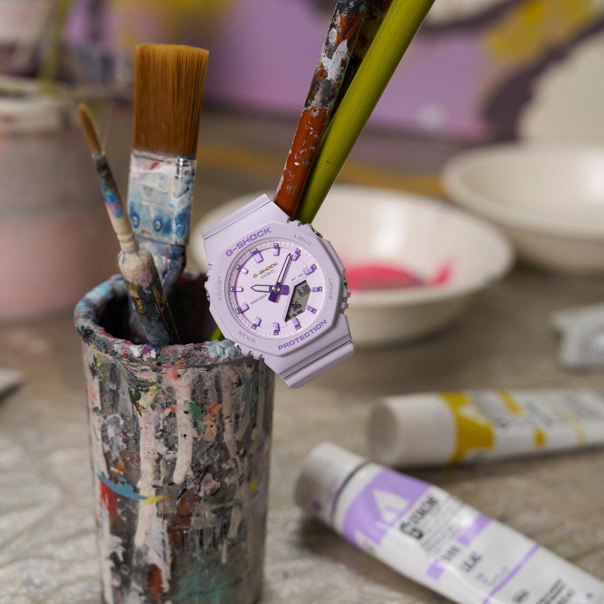 El GMA-P2125W-6AER ​​morado cuelga de dos cepillos que se encuentran en un recipiente para cepillos.