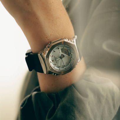 Primer plano del GM-S2110-2AER en la muñeca izquierda de una mujer. Ella lleva el reloj combinado con una chaqueta verde. 