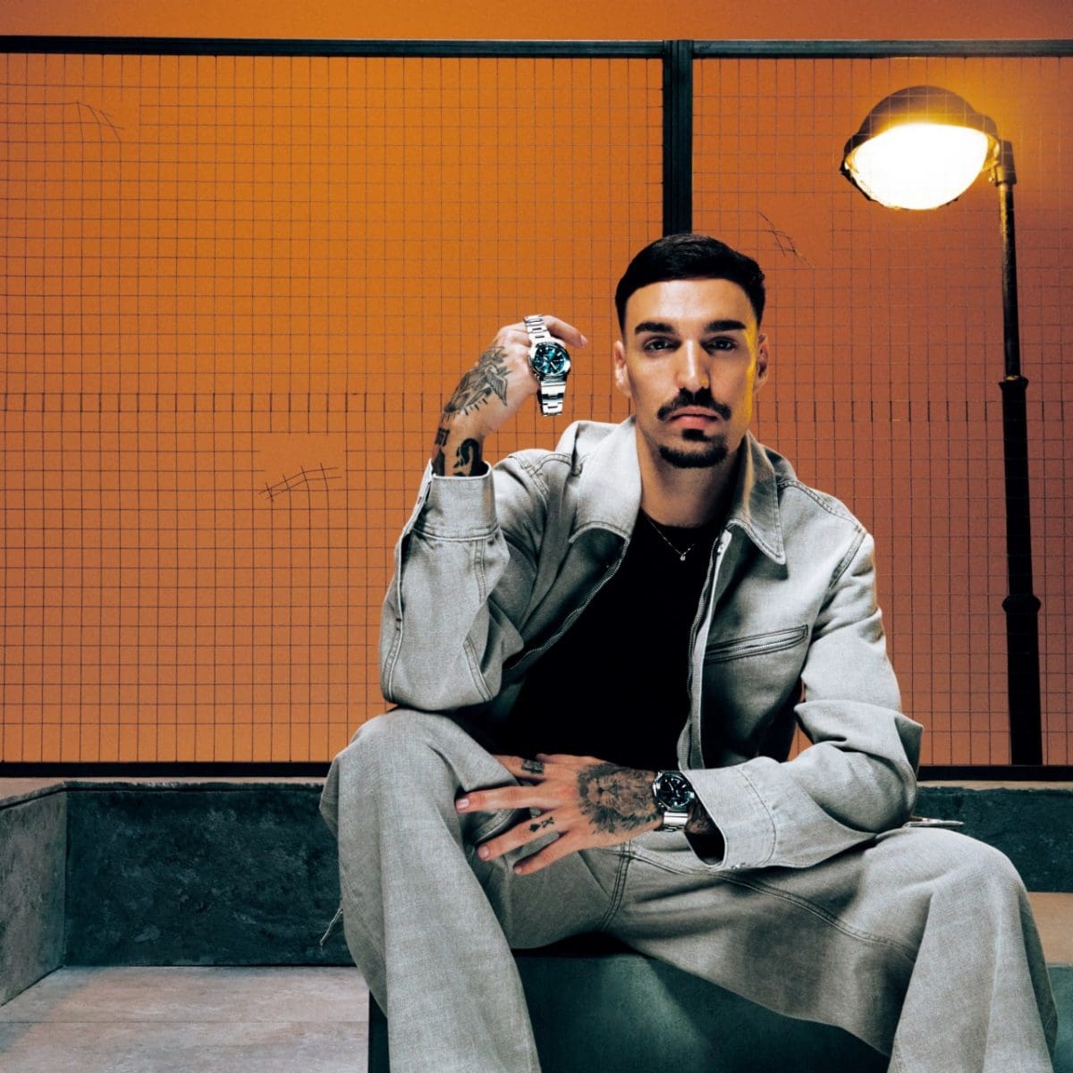 Rels B lleva el GM-2110D-3A1ER y está sentado delante de un fondo naranja.