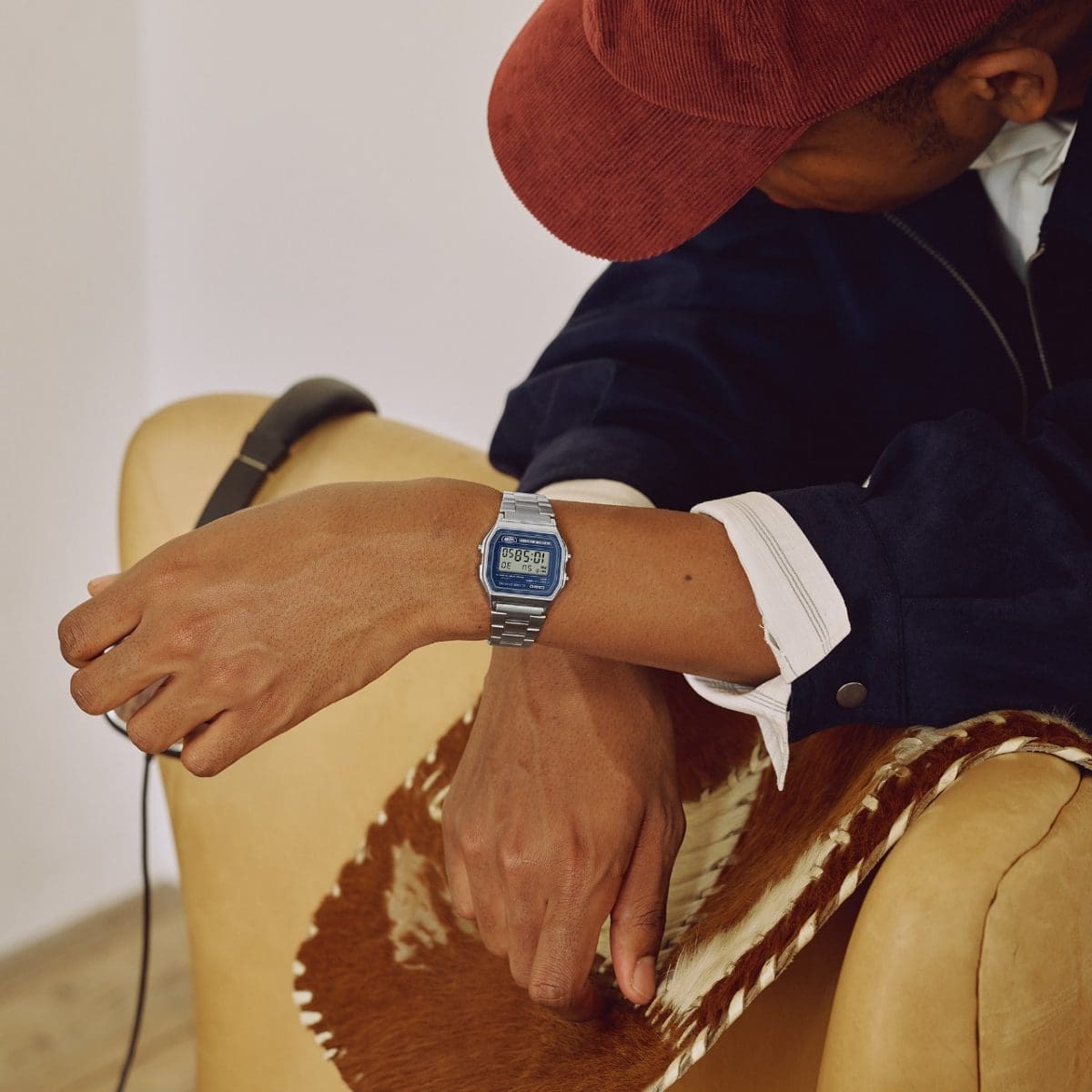 A man is wearing the A158WEA-2EF on his wrist and has his forearms resting on the back of a chair.