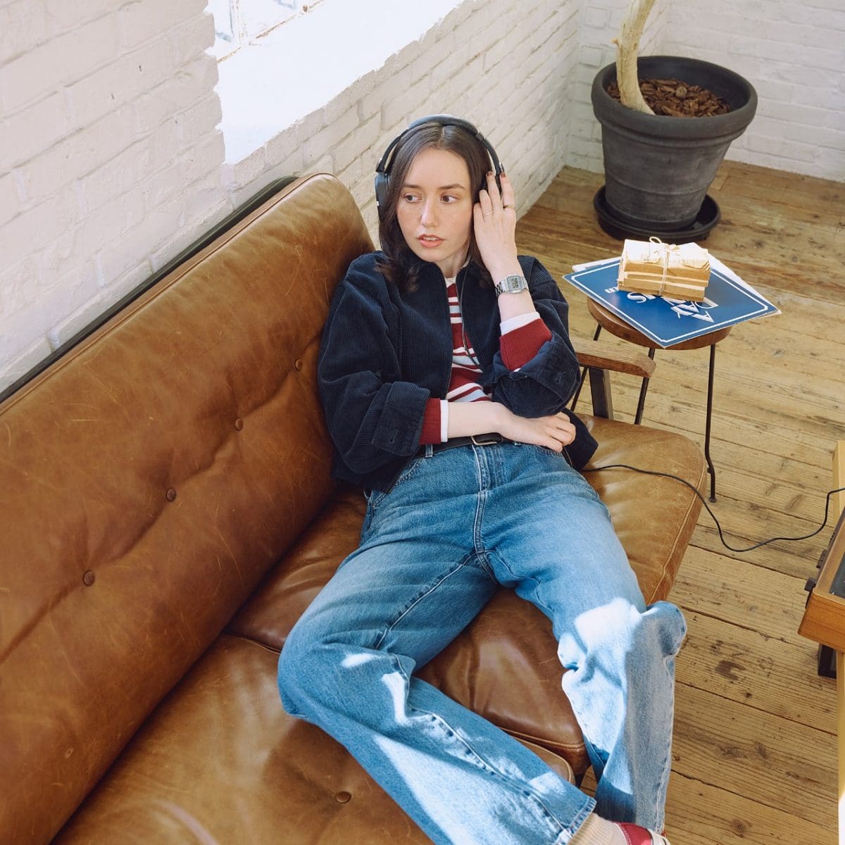 A woman is wearing the A158WEA-7EF on her wrist and is lying on a sofa with headphones on.