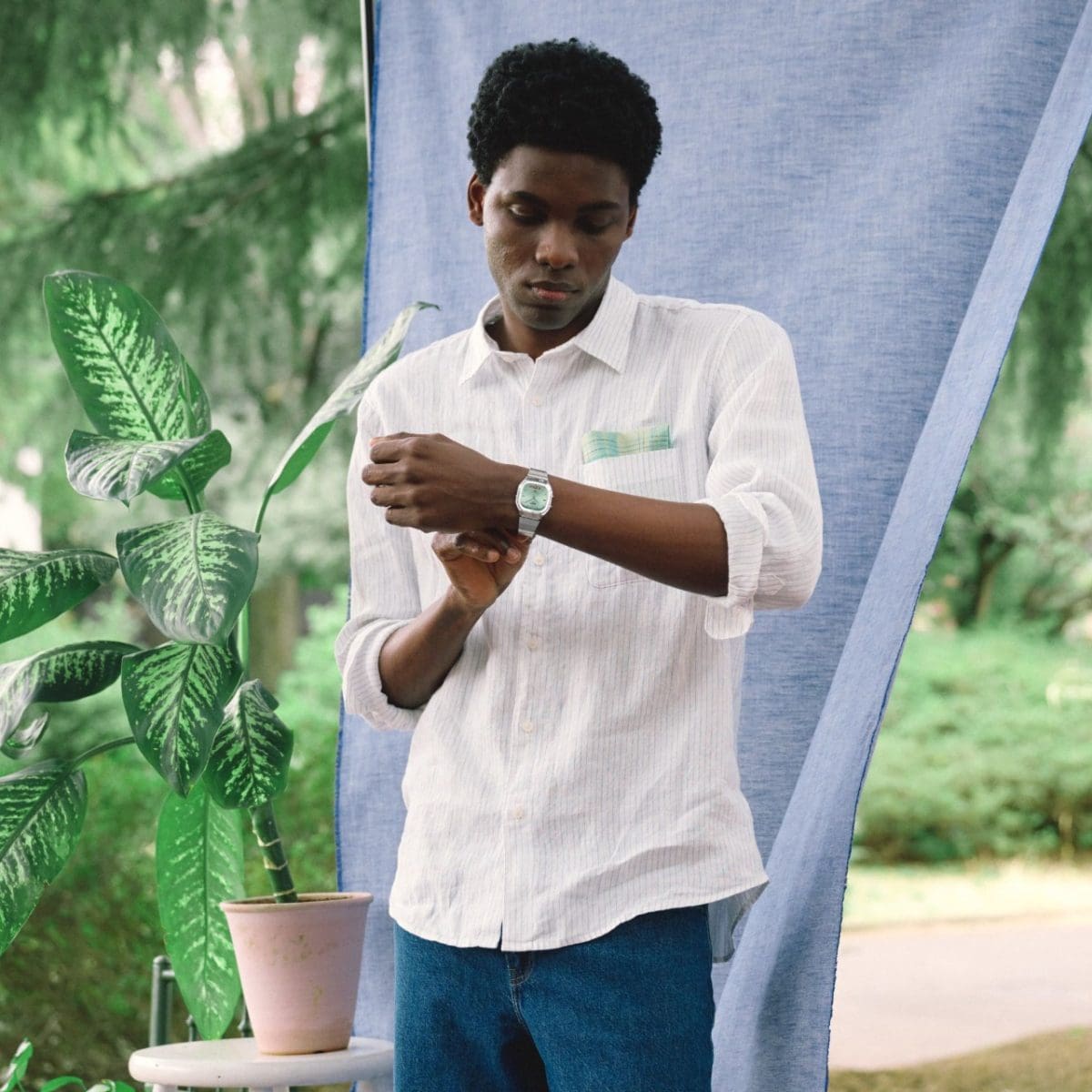A dark-skinned man wearing a white shirt and blue jeans is wearing the AQ-240E-2AEF wristwatch on his wrist.