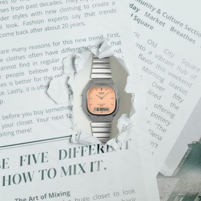 The analog-digital wristwatch AQ-240E-4AEF looks through a hole torn in a newspaper.