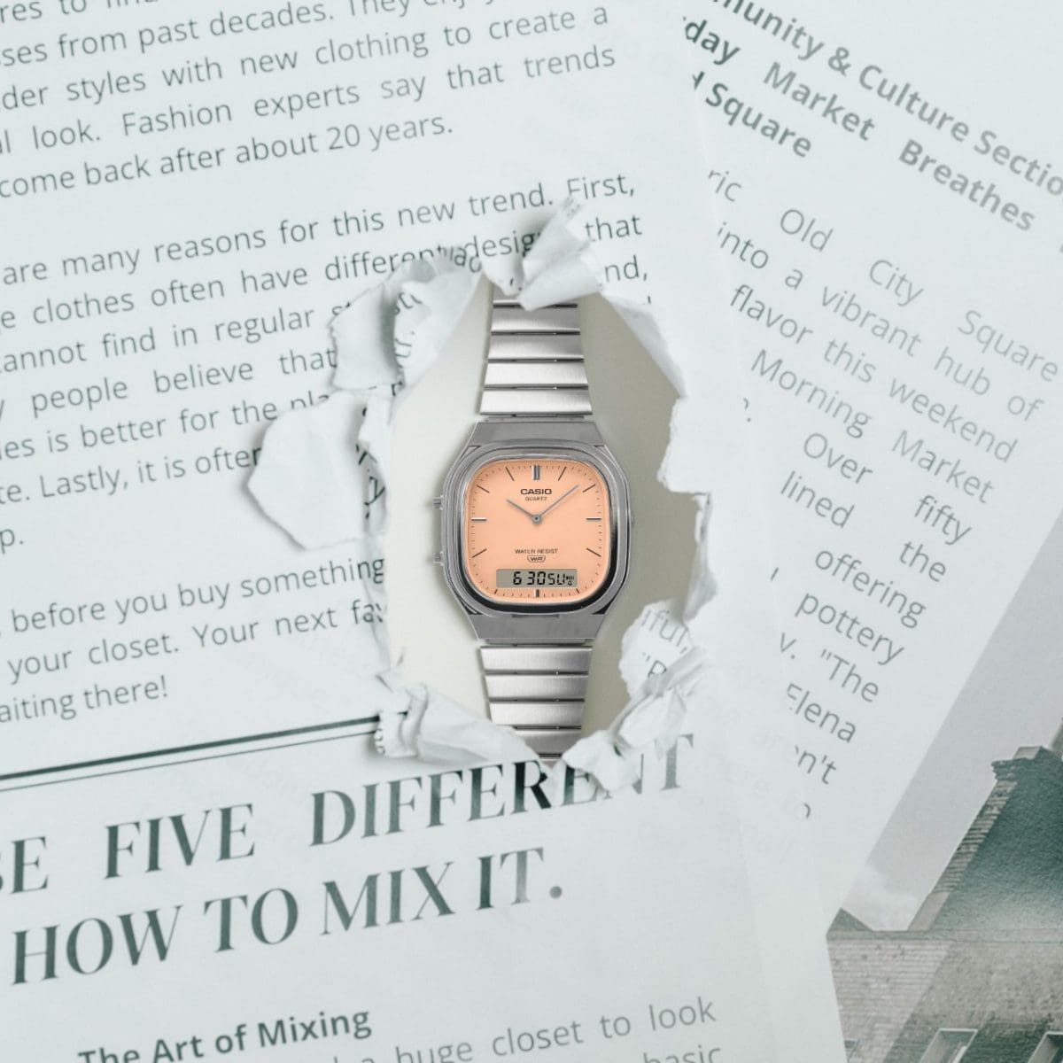The analog-digital wristwatch AQ-240E-4AEF looks through a hole torn in a newspaper.