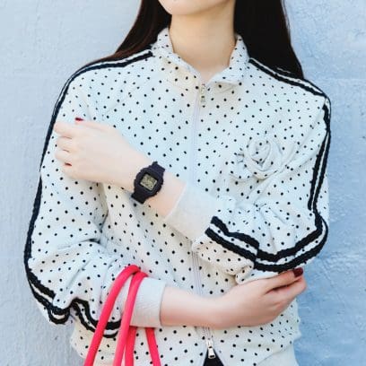 A woman wearing a white jacket with black dots wears the BGD-10KH-2CER on her wrist.