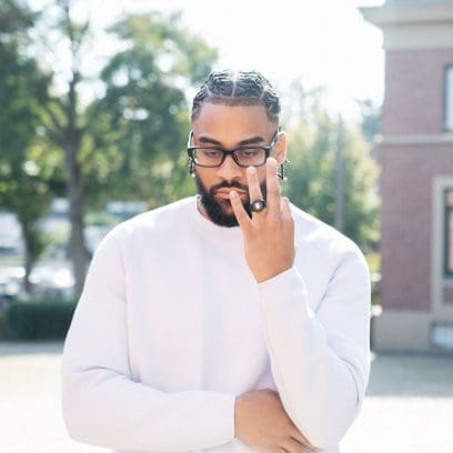 A man wears the DWN-5600-1 on his ring finger and has a white sweater on
