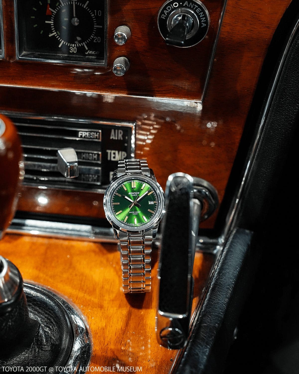 The wristwatch EFR-109D-3A from EDIFICE stands on a wooden center console of an old car