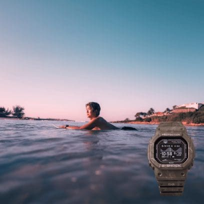 Surfer Kanoa Igarashi is lying on his surfboard in the water, and the GBX-H5600KI-5ER wristwatch is shown in the lower right corner of the image.