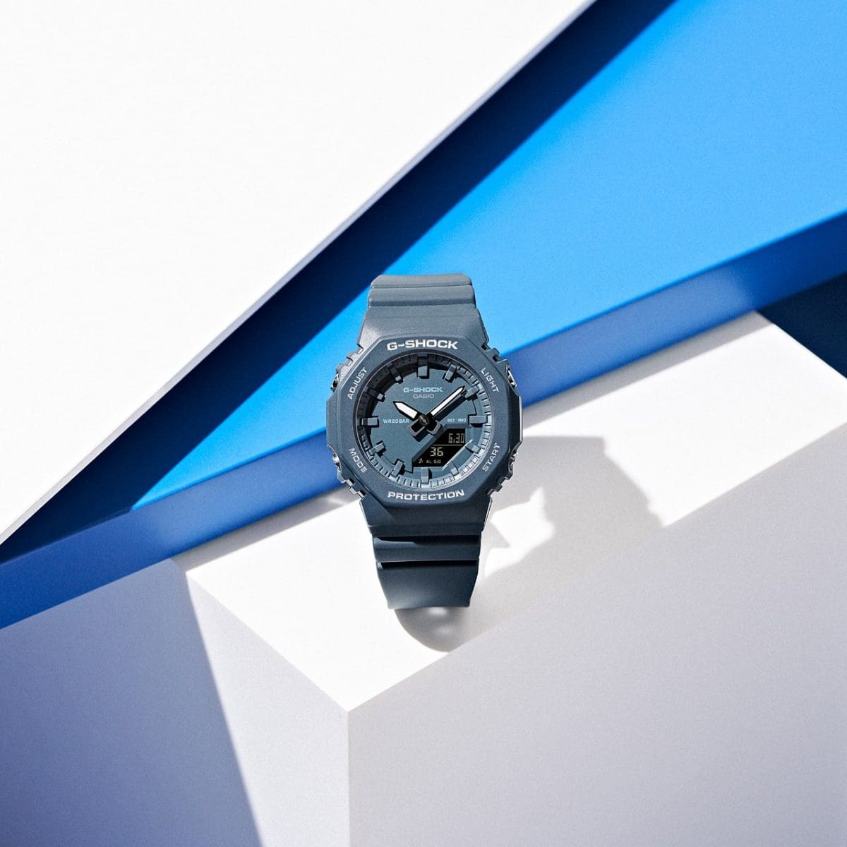 The GMA-P2100BA-2AER stands in front of white and blue geometric shapes.