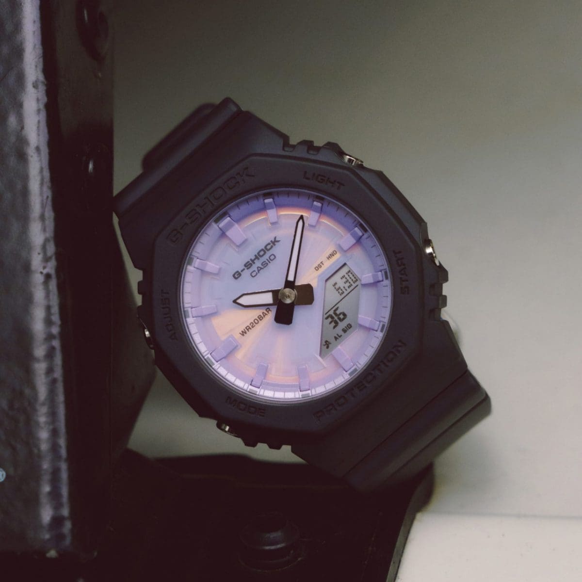 Front view of the black GMA-P2100PC-1AER with purple dial placed diagonally against a black object
