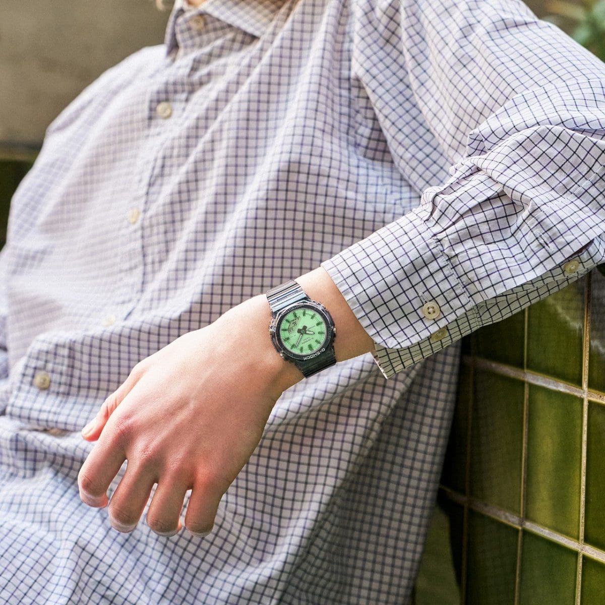 A man wearing a checkered shirt is wearing the G-SHOCK GMA-P2100SR-1AER analog-digital wristwatch on his wrist.