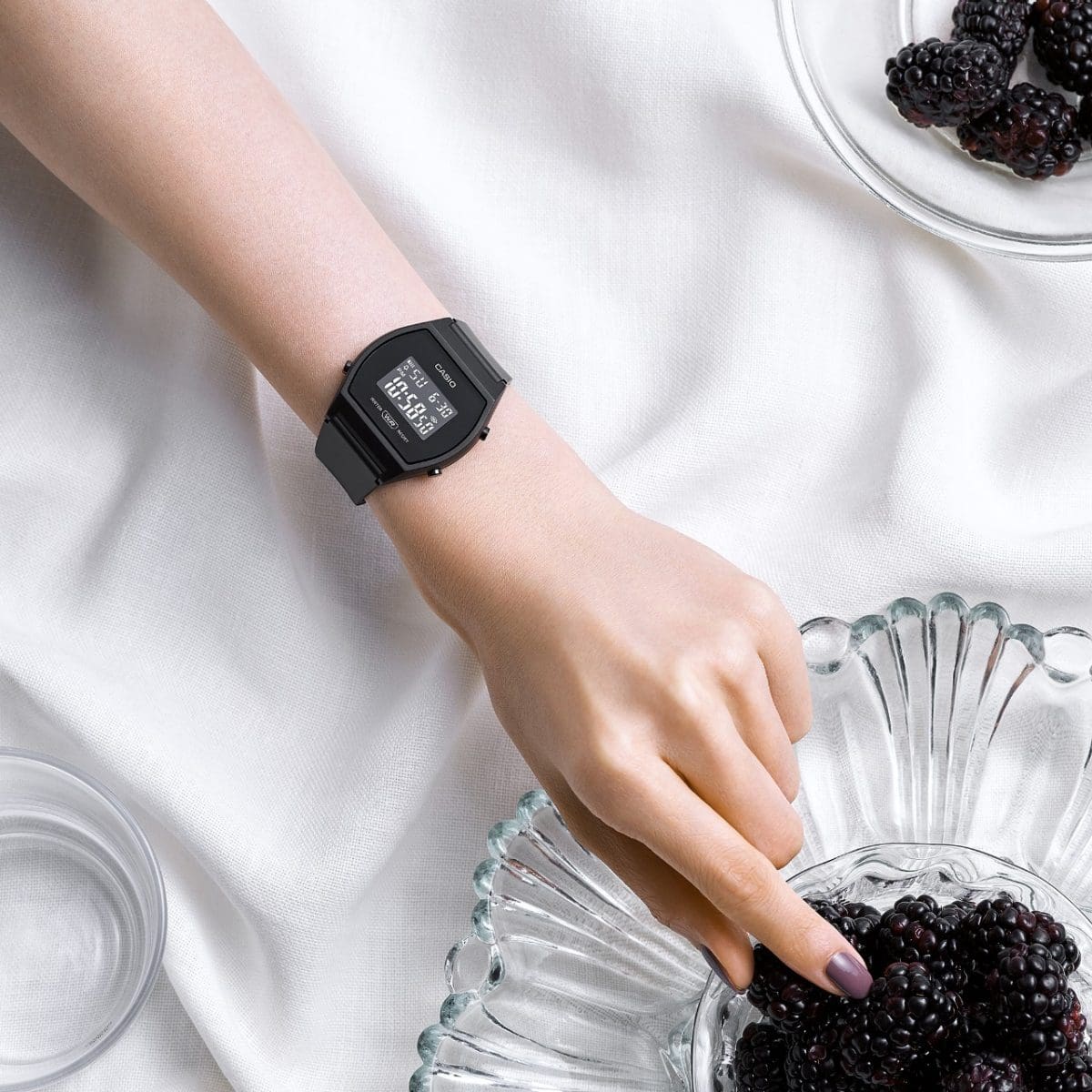 A woman wears the LW-204-1B on her wrist and reaches into a bowl of blackberries