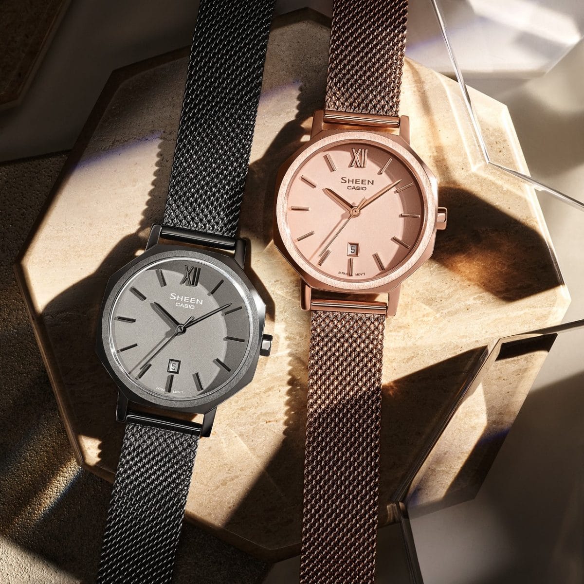 From the left, the SHE-4554GYM-8A and SHE-4554PGM-4A wristwatches on a wooden base.