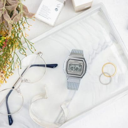 Vue de face de la montre en argent A1000MA-7 posée sur un plateau à côté de lunettes et de bijoux