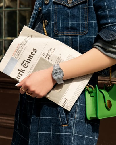 Une femme portant l'A1000MA-7 argentée tient un journal et porte des bijoux en or.