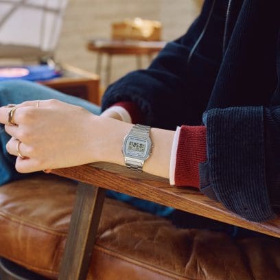 Une femme porte le bracelet A158WEA-7EF et a le bras appuyé sur le dossier d'une chaise.