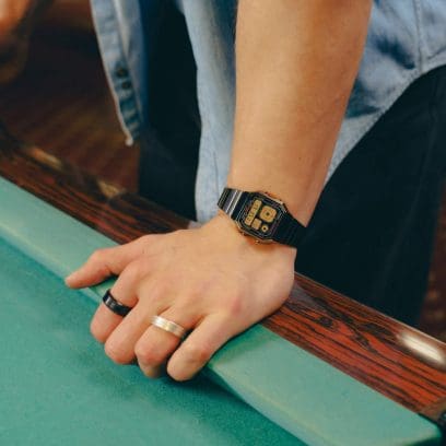 Le A130WEGG-1AEF au poignet d'un homme portant une bague en or et une bague en argent au doigt