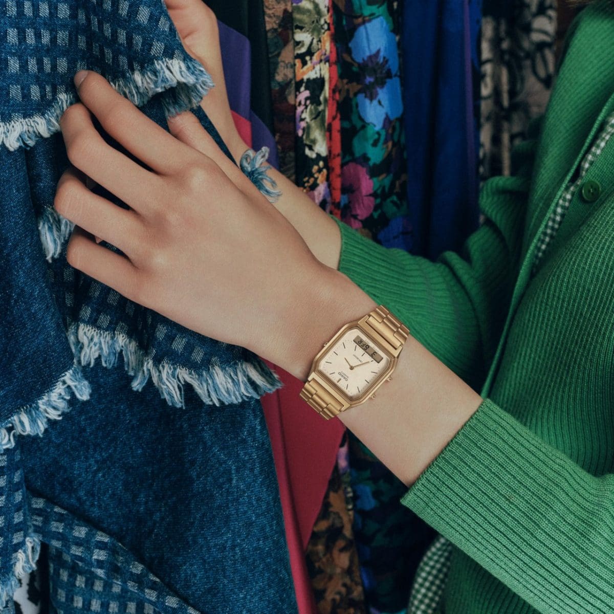 Une femme choisit des vêtements. Elle porte au poignet l’AQ-230A-7AMQY, une montre analogique dorée issue de la CASIO Vintage Collection. 
