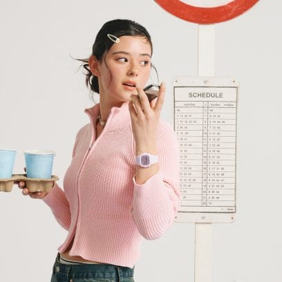 Une femme portant un cardigan rose parle au téléphone portable et a la montre numérique BABY-G BGD-565SC-4BER au poignet.