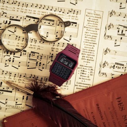 Le rouge montre CA-53WF-4B de CASIO Vintage Collection sur une table, à côté de notes de musique