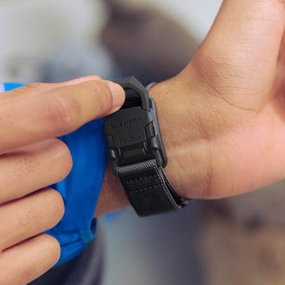 Un homme porte la montre numérique DW-5600MNC-1ER à son poignet et ferme le fermoir magnétique FIDLOCK® d'une seule main.