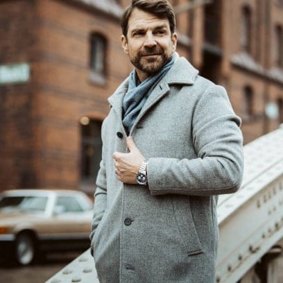 La montre chronographe EFR-575D-2AEF avec bracelet en métal au poignet d'un homme se tenant devant un bâtiment en briques.