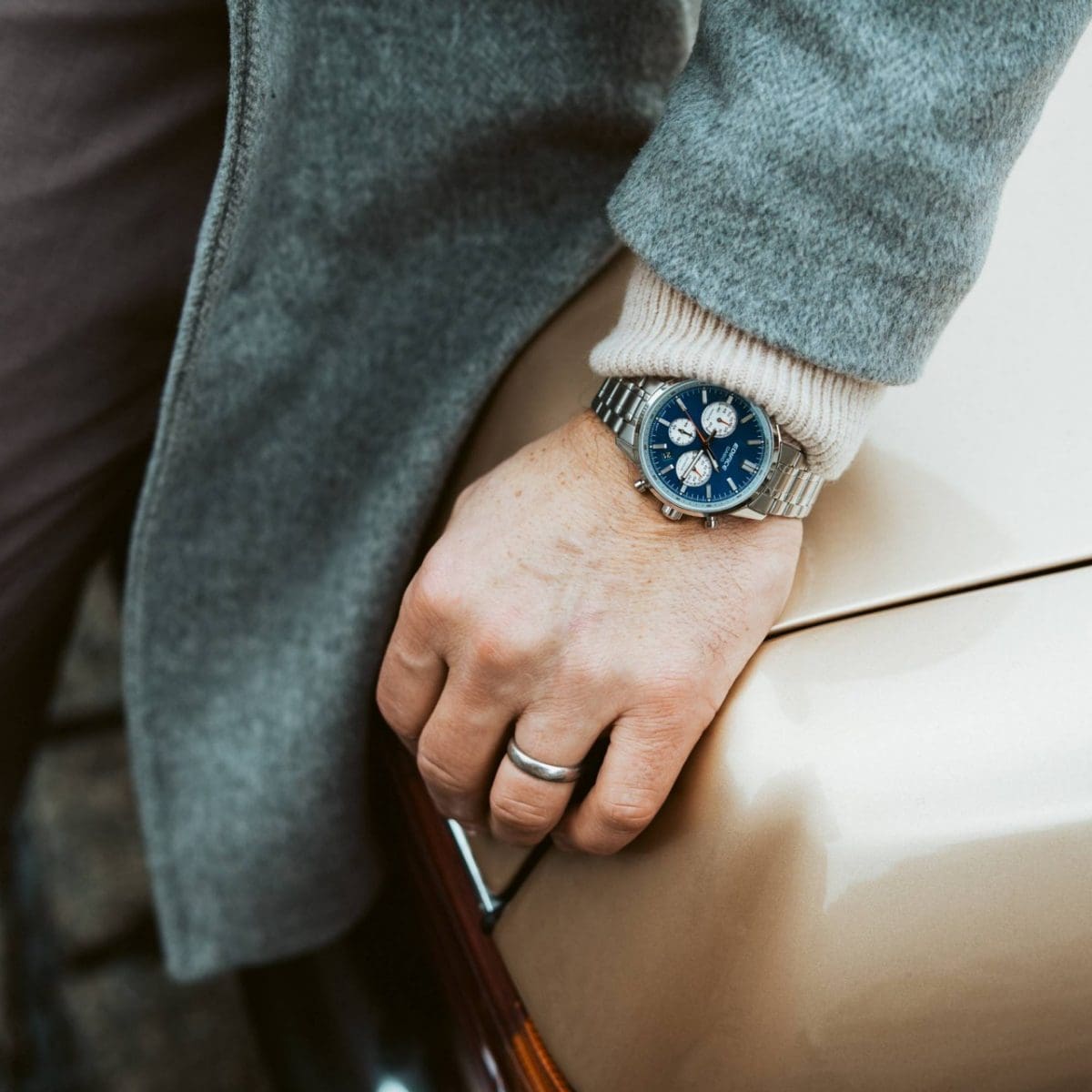 Gros plan sur la montre bleue EDIFICE EFR-575D-2AEF au poignet d'un homme portant un manteau de laine gris.