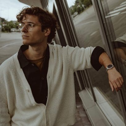 Un homme porte l'EFK-100CD-1AER et porte un cardigan blanc sur une chemise noire