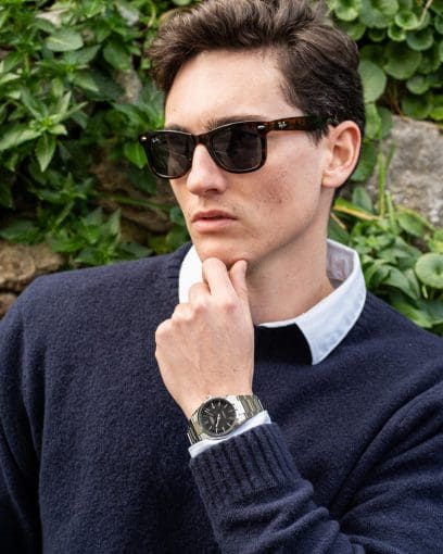 Un homme portant un pull en laine bleu foncé et des lunettes de soleil noires porte la montre analogique EFK-110D-1A au poignet