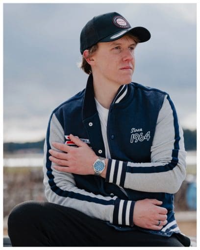 Un homme est assis dehors, vêtu d'un sweat-shirt de sport et d'une casquette, et porte la montre-bracelet EDIFICE EQB-1300D-2AEF au poignet.