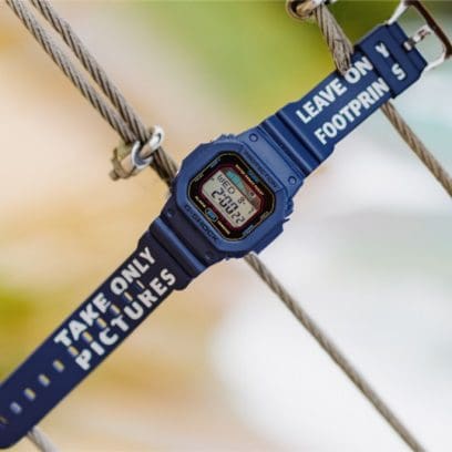 La montre G-SHOCK GLX-5600WHR24-2ER avec un bracelet bleu sur lequel est inscrit en blanc « take only pictures - leave only footprints ».