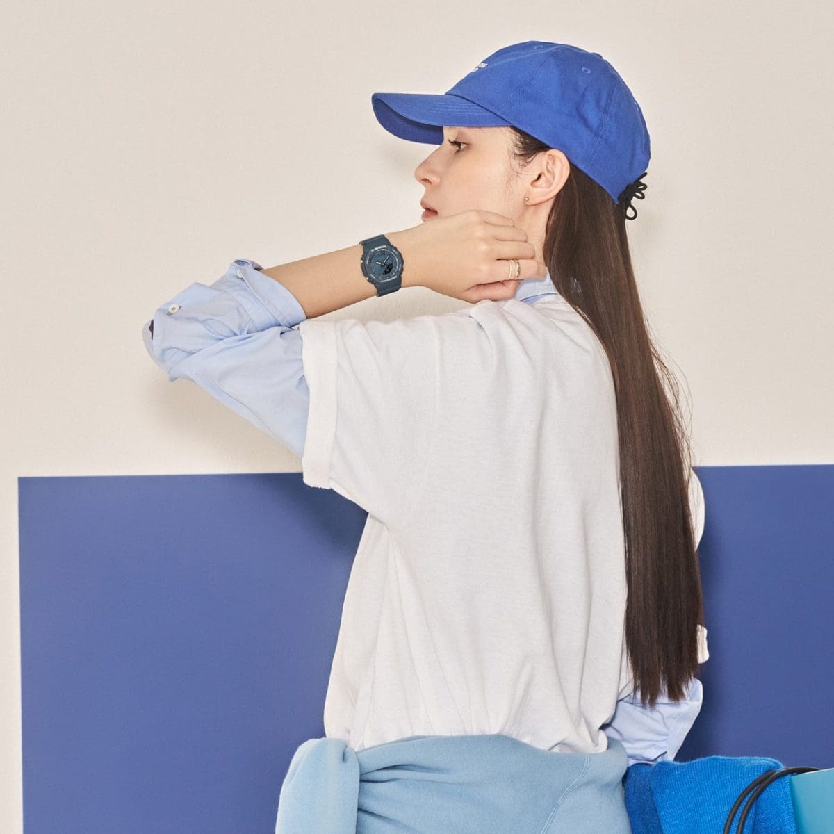 Une femme portant un t-shirt blanc sur une chemise bleu clair porte la montre GMA-P2100BA-2AER à son poignet.