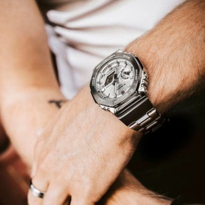 GM-2110D-7AER Full-Metal G-SHOCK avec bracelet argenté et cadran argenté au poignet d'un homme