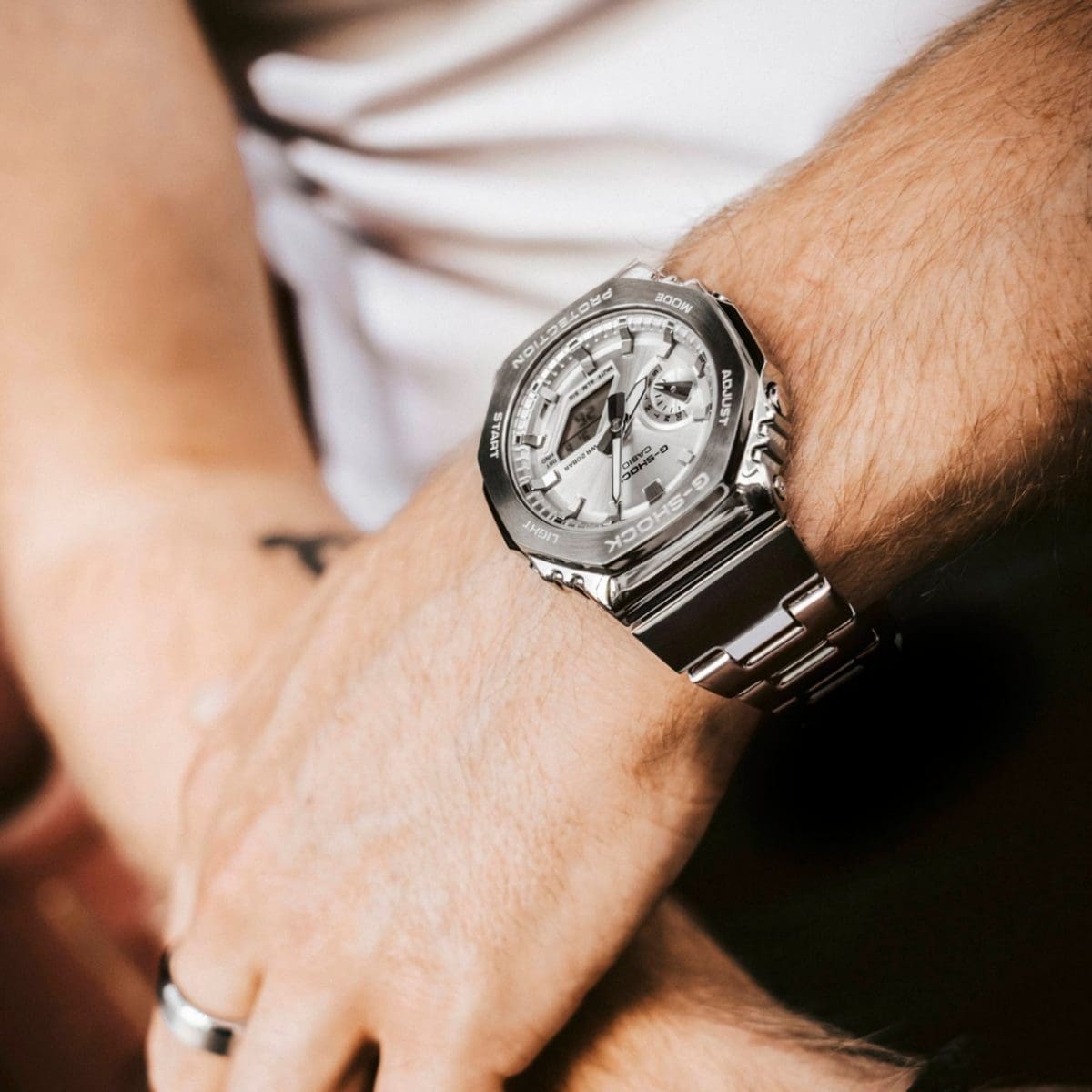 GM-2110D-7AER Full-Metal G-SHOCK avec bracelet argenté et cadran argenté au poignet d'un homme