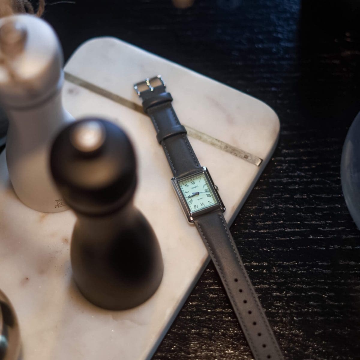 La montre-bracelet "LTP-B165L-2BV" de CASIO Collection est posée à côté d'un moulin à sel et à poivre sur un fond en marbre.
