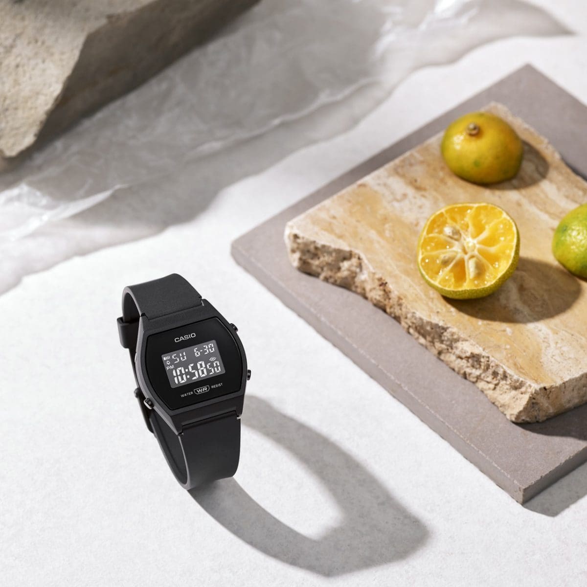 Le LW-204-1B est posé sur une table, son bracelet fermé. Des citrons verts sont posés à côté, sur une dalle de pierre.