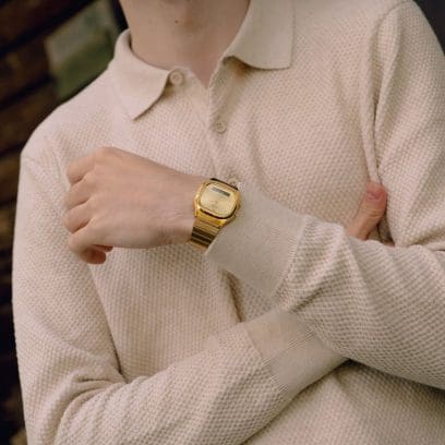 Un uomo con un maglione beige lavorato a maglia indossa l'AQ-240EG-9AEF dorato al polso