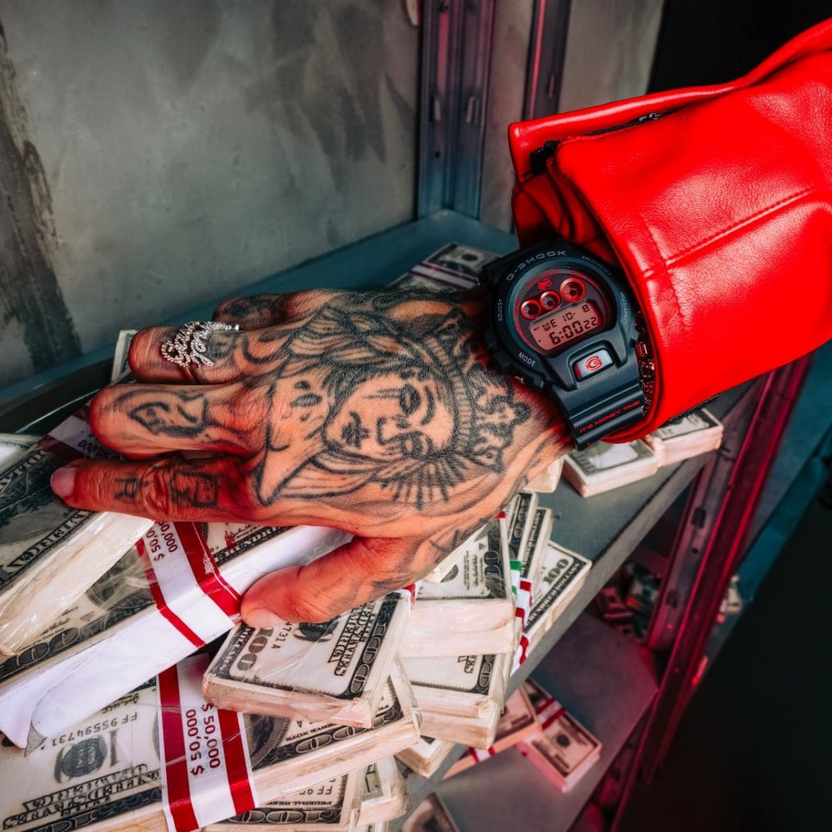 Un uomo con una mano tatuata indossa il DW-6900SFE25-1 al polso e tiene la mano appoggiata su una pila di banconote.
