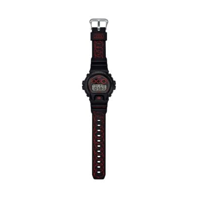 Una vista completa del DW-6900SFE25-1 con il bracciale aperto. Il bracciale nero presenta un motivo a filo spinato rosso disposto ad anelli. La scritta "It's Money Time" è stampata all'incrocio tra il bracciale e la cassa.