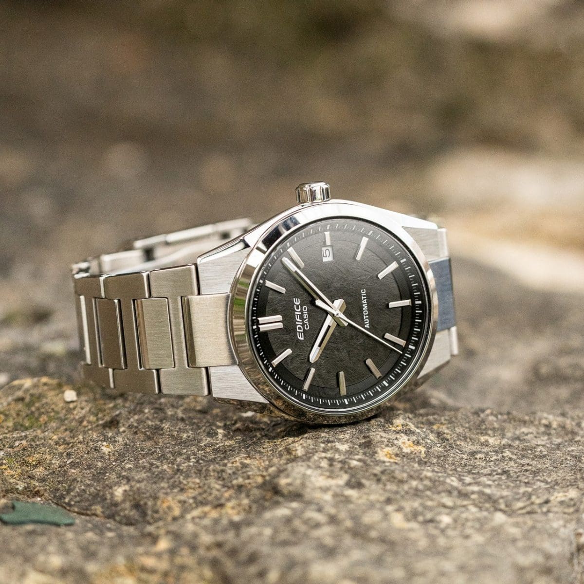 L'orologio da polso EDIFICE EFK-110D-1A è appoggiato su un lato su una superficie di pietra