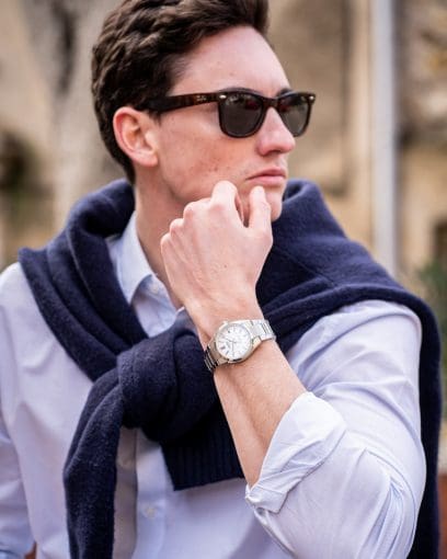 Un uomo che indossa una camicia azzurra e un maglione blu scuro sulle spalle indossa l'EDIFICE EFK-110D-7A al polso